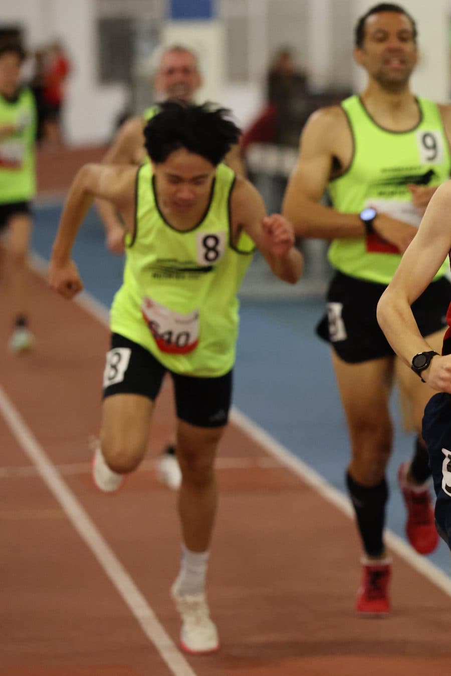 Me in the neon Huskies singlet, #8, driving for the line at an indoor meet