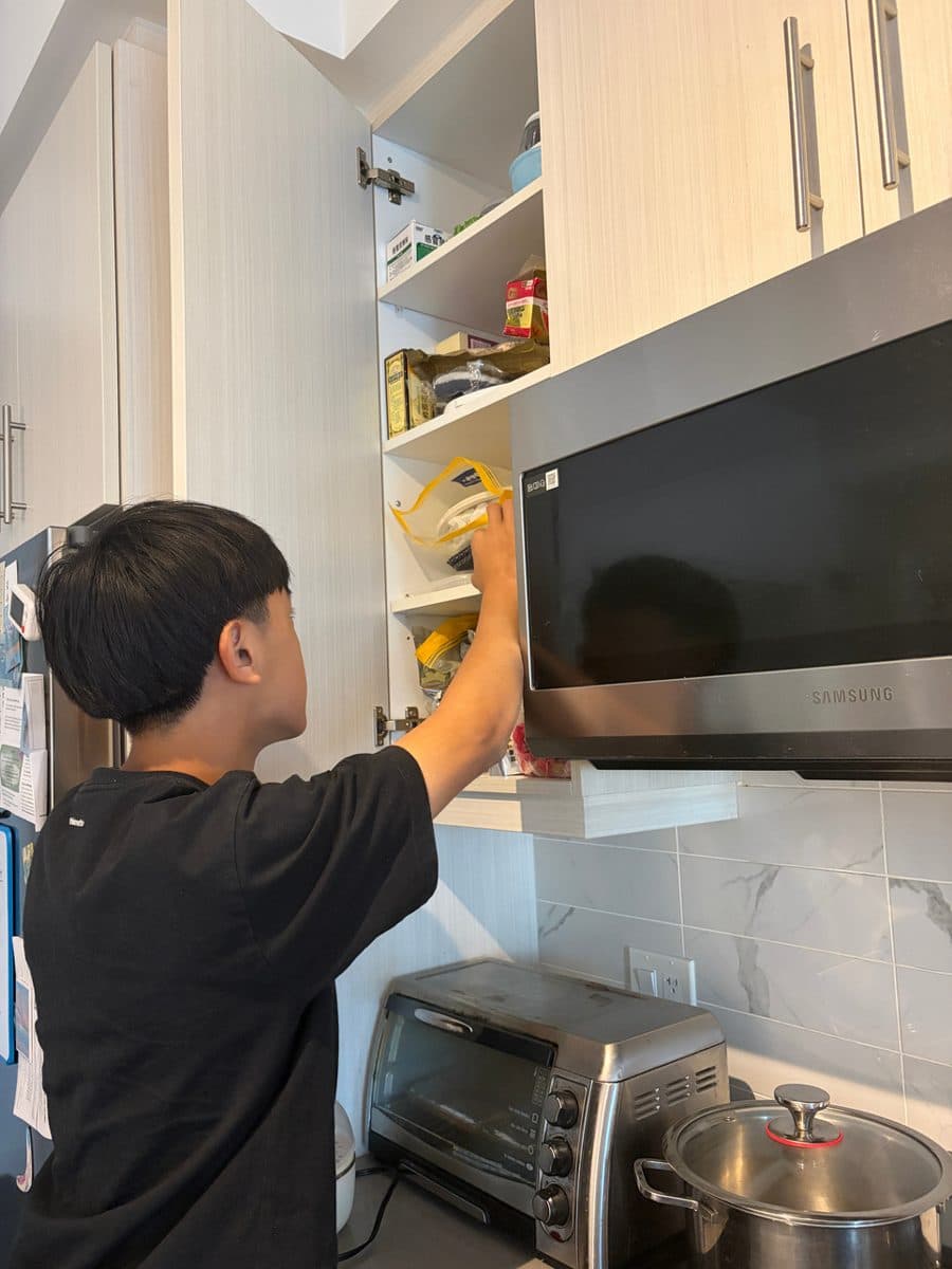 Brighton reaching for snacks in a kitchen cupboard