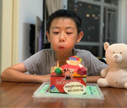 Me blowing out birthday candles with Brother next to the cake