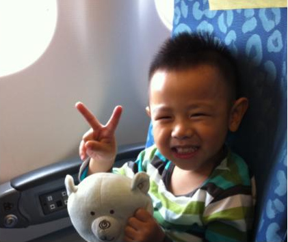 Me as a toddler on a plane, holding Brother and making a peace sign